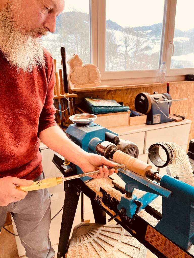 Un homme est en train de réaliser une pièce en tournage sur le bois lors d'un atelier découverte de WoodyWoodPeg.