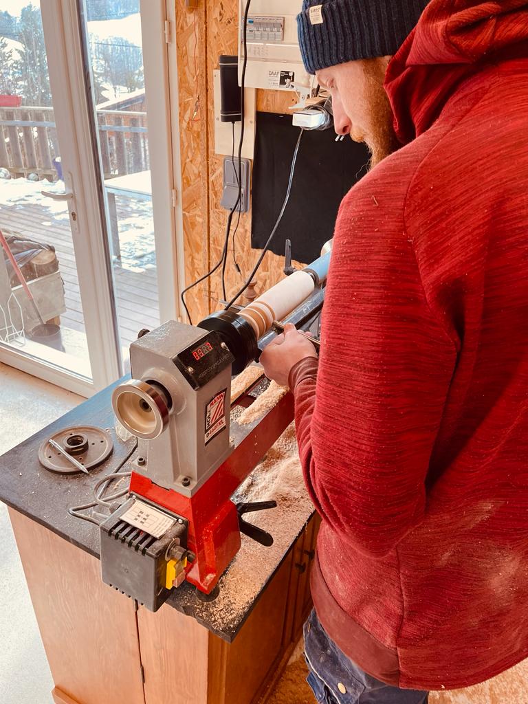 Un homme est en train de réaliser une pièce en tournage sur le bois lors d'un atelier découverte de WoodyWoodPeg.
