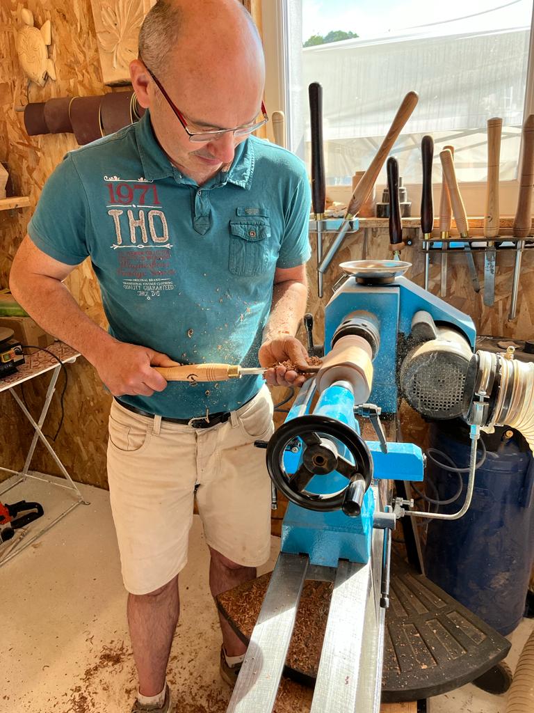 Un homme est en train de réaliser une pièce en tournage sur le bois lors d'un atelier découverte de WoodyWoodPeg.